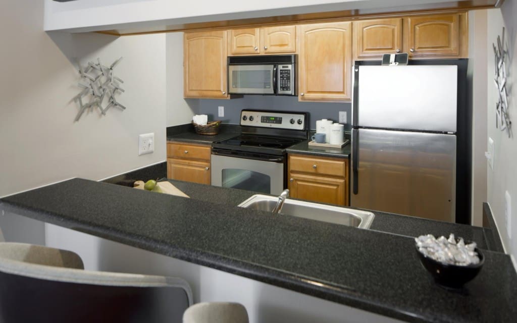 Pet-Friendly Apartments in Centreville - Lakeside - Kitchen with Black Countertops, Brown Cabinets, Breakfast Bar, and Appliances.